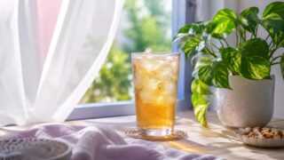 涼やかな夏の朝の窓辺。冷たい麦茶のグラスと観葉植物、そよぐ白いカーテン